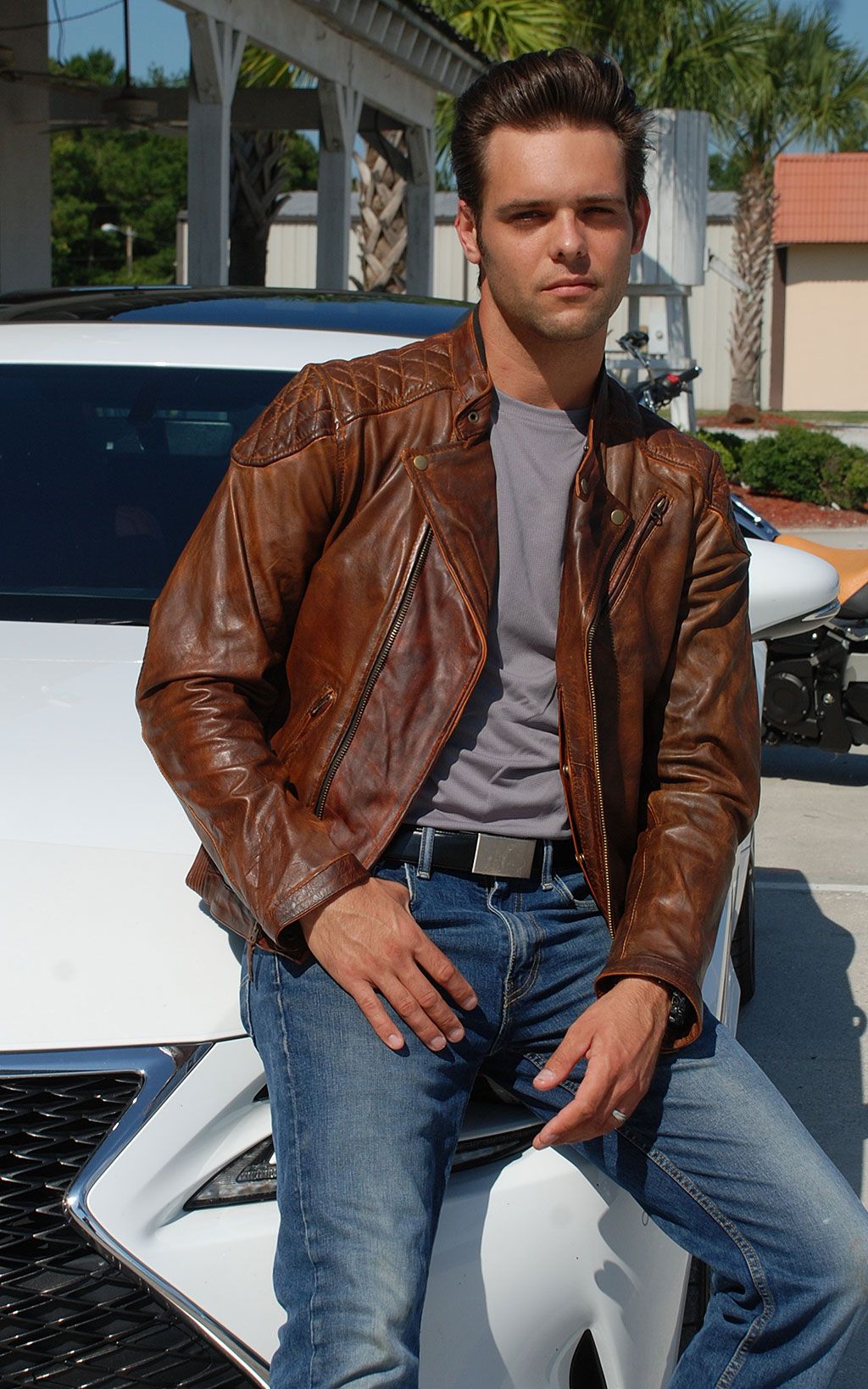 Biker wearing brown leather jacket on a car